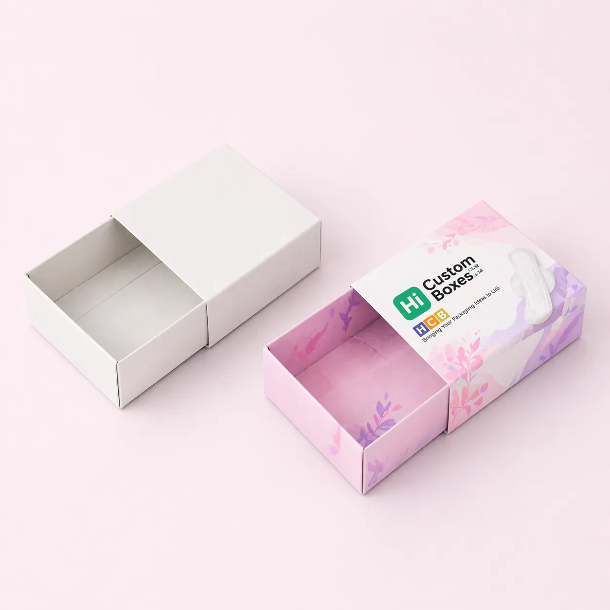 Two small cardboard boxes, one blank and one with purple floral designs and product branding details. class=